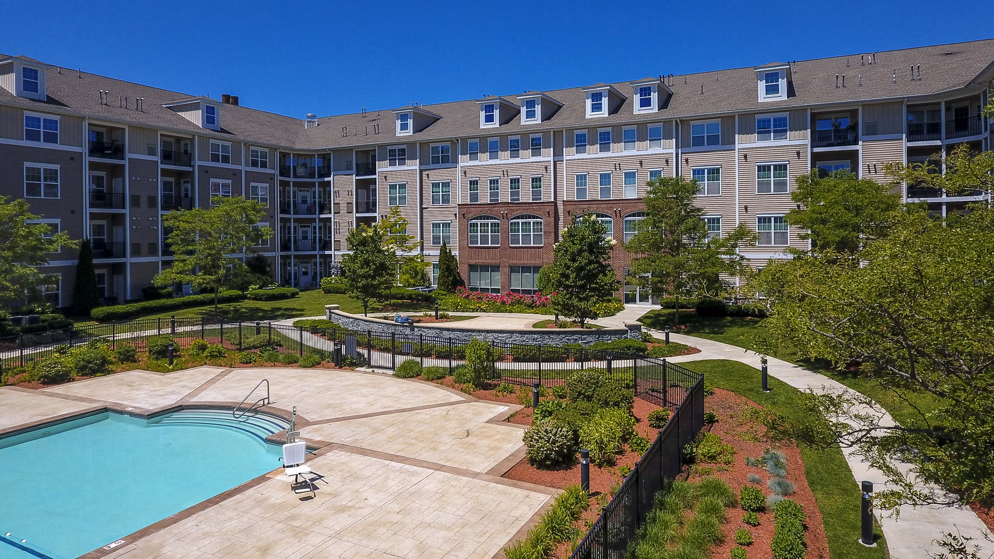 Swimming pool area with red Adirondack chairs and a modern apartment building in the backdrop