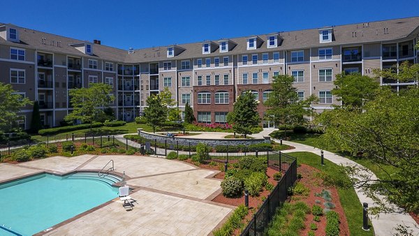 Swimming pool area with red Adirondack chairs and a modern apartment building in the backdrop