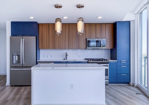 Kitchen with modern appliances and sleek countertops at Illume Apartments