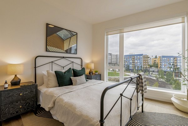 Modern bedroom with plush bedding and large windows at Verde Esterra Park Apartments