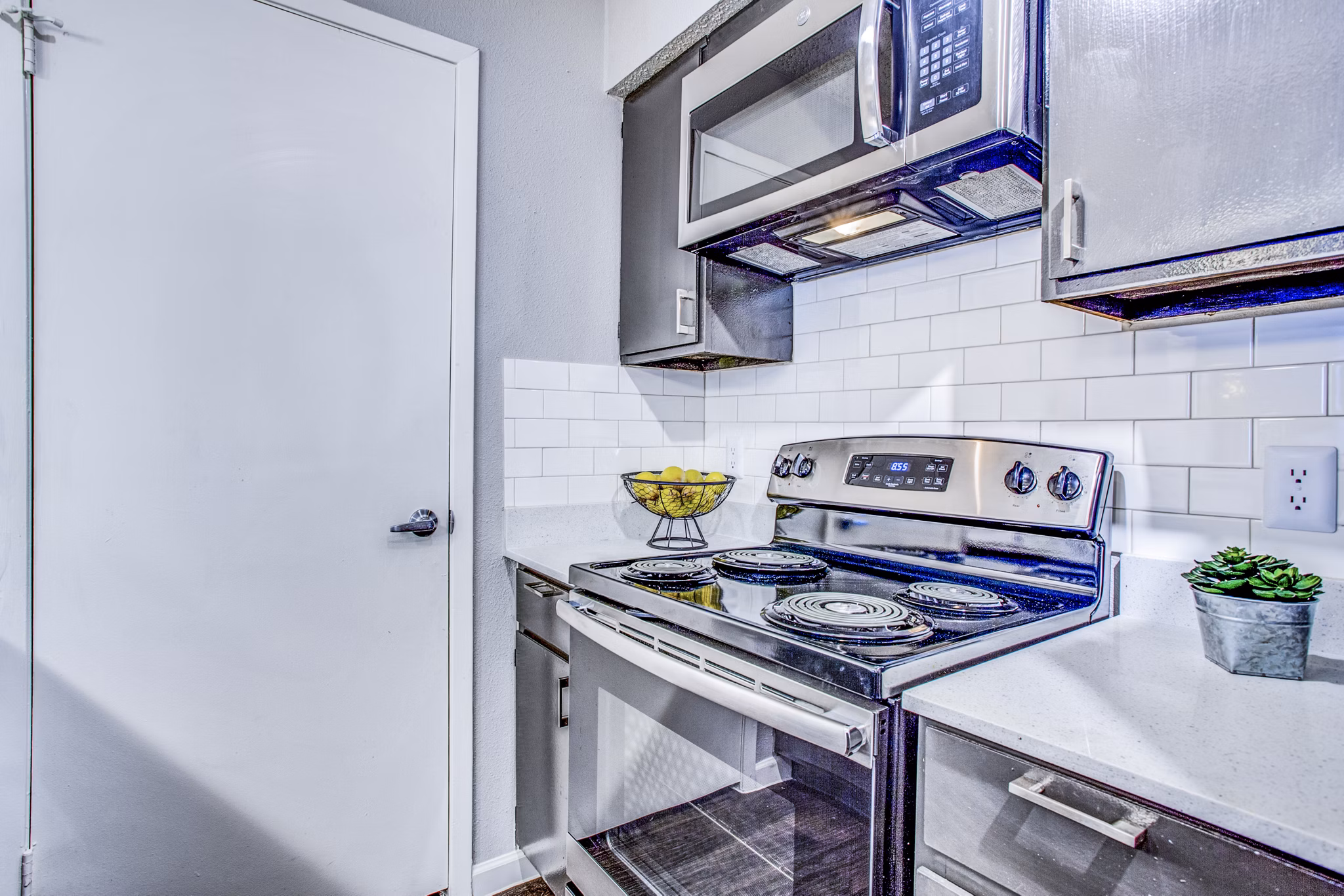 Modern kitchen with stainless steel appliances and quartz countertops at The Oakley Apartments