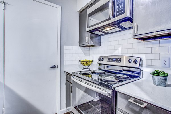Modern kitchen with stainless steel appliances and quartz countertops at The Oakley Apartments