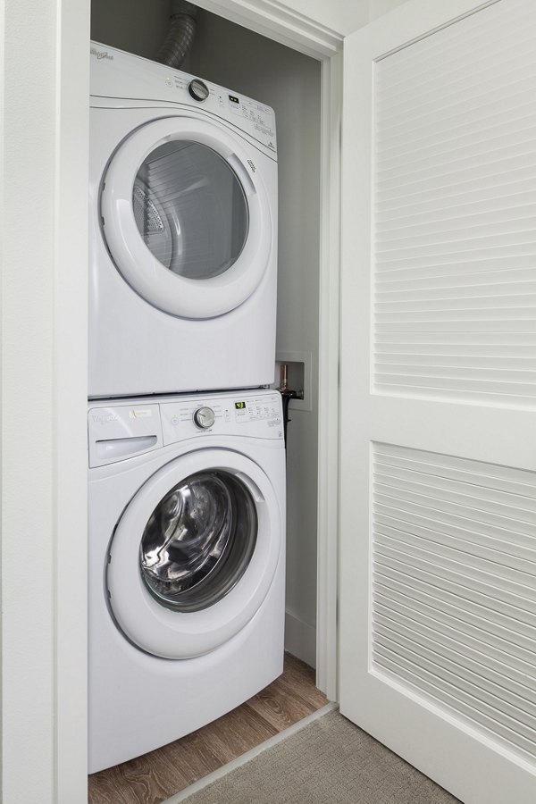 Modern laundry room with high-efficiency washers and dryers at Spencer 68 Apartments