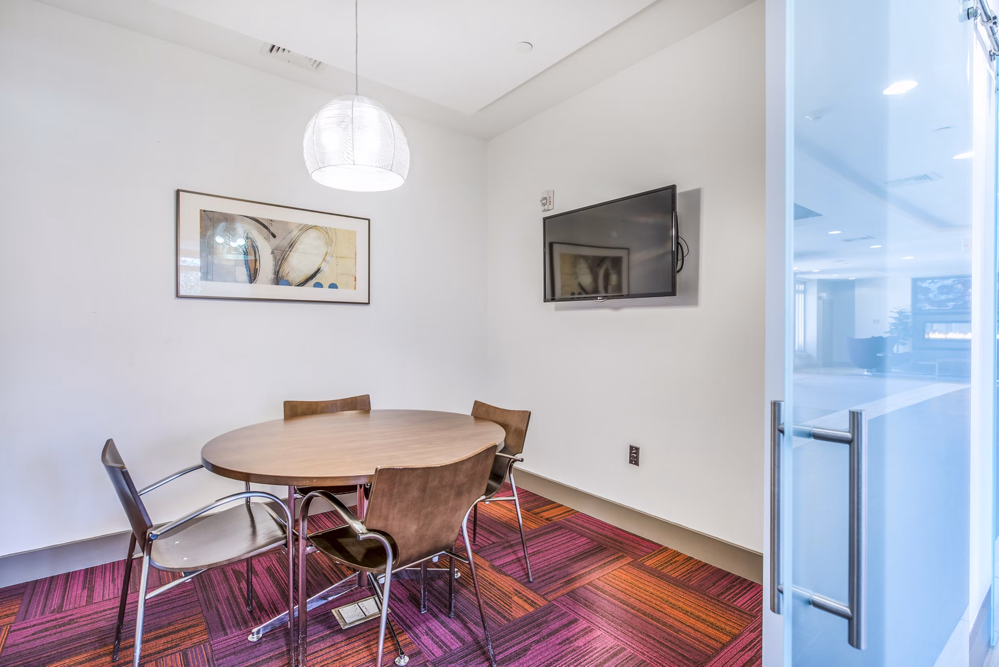 Clubhouse meeting facility at Atmark Apartments: Modern space for gatherings with seating and digital displays in luxury Cambridge community