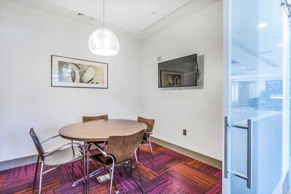 Clubhouse meeting facility at Atmark Apartments: Modern space for gatherings with seating and digital displays in luxury Cambridge community