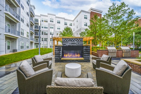 Outdoor fire pit and grill area at Atmark Apartments: Ideal communal space for gatherings and relaxation in Cambridge, MA