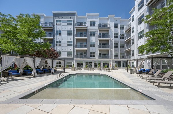 Modern outdoor pool with lounge chairs at Atmark Apartments, perfect for relaxation and leisure in a luxury setting