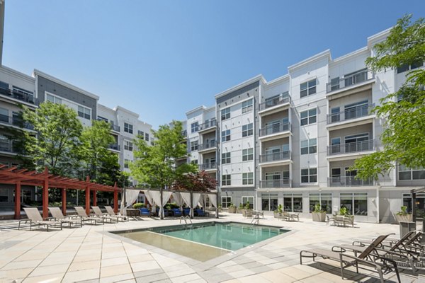 Resort-style pool with sun loungers at Atmark Apartments, offering luxurious amenities in a vibrant community setting
