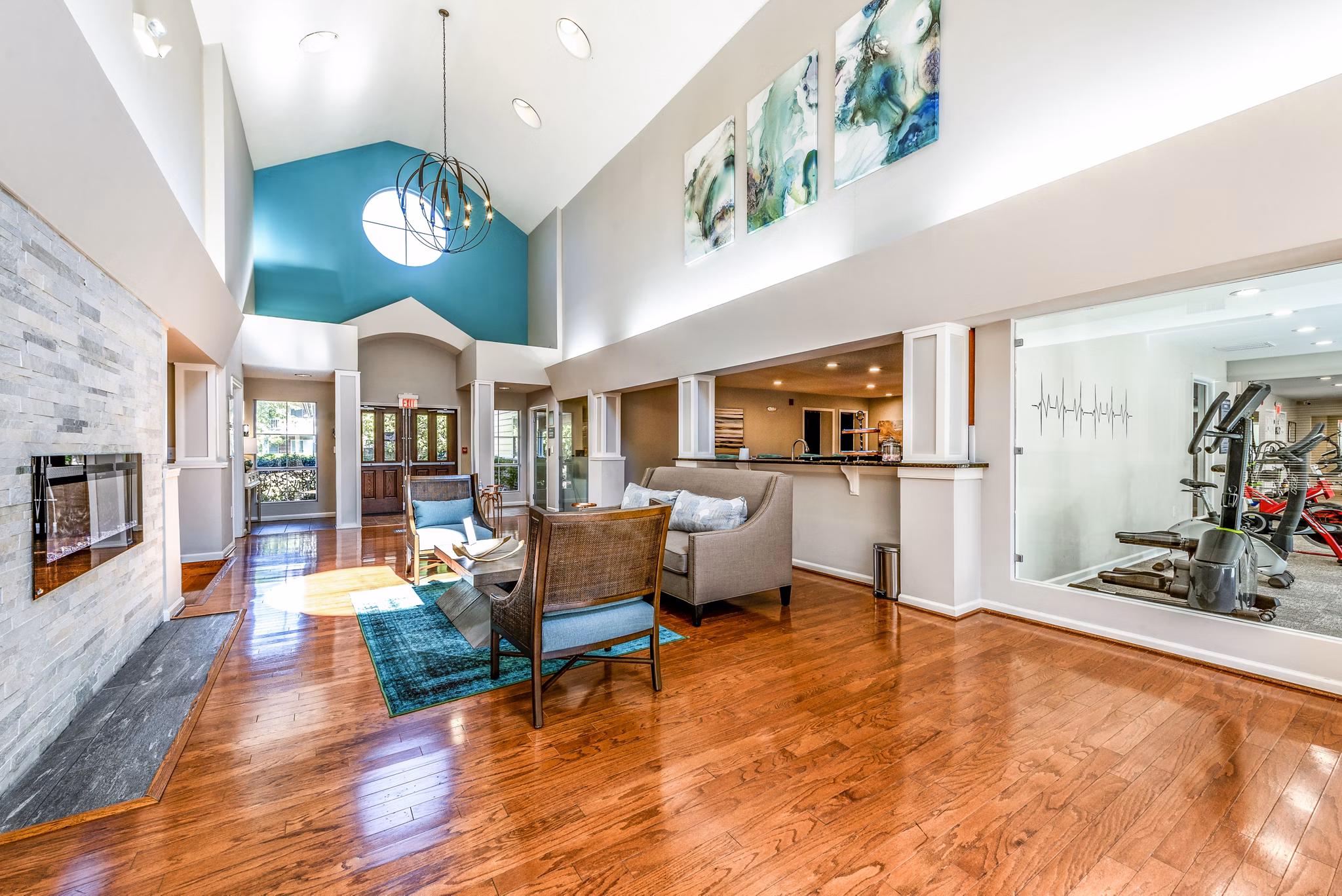 Modern living room with high ceilings, fireplace, and gym view in luxury apartments