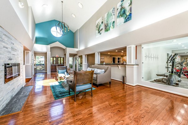 Modern living room with high ceilings, fireplace, and gym view in luxury apartments