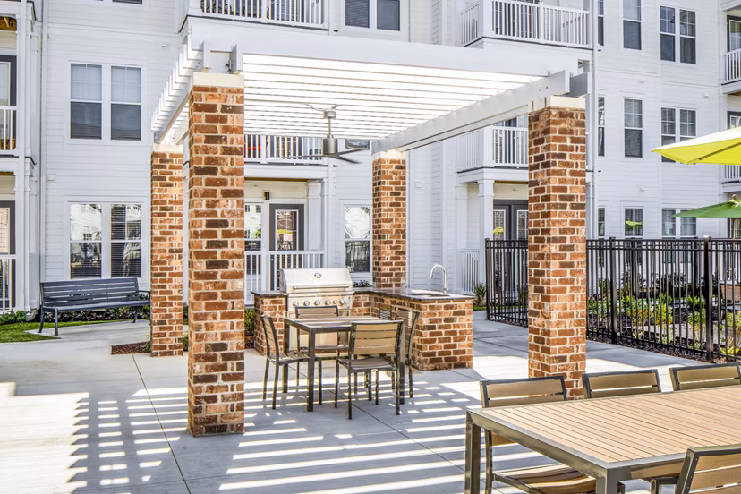 Community grilling area at Album Indian Lake Apartments featuring modern patio furnishings and lush landscaping