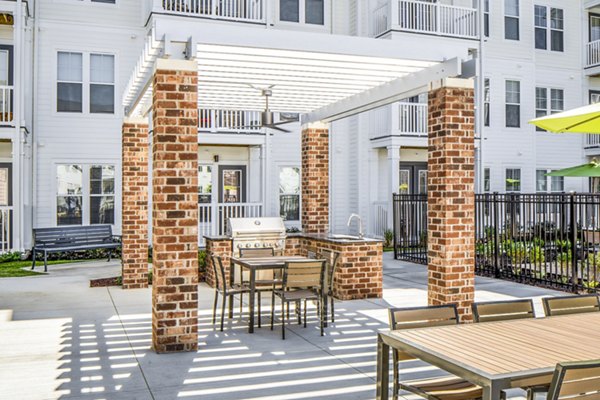 Community grilling area at Album Indian Lake Apartments featuring modern patio furnishings and lush landscaping