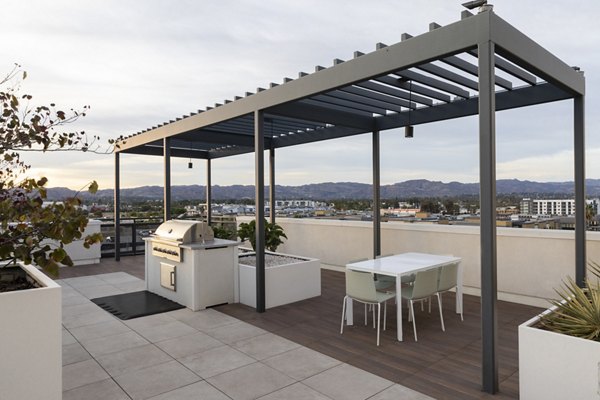 Grill area with modern seating and greenery at Vert Apartments, perfect for outdoor gatherings and relaxation in luxury surroundings
