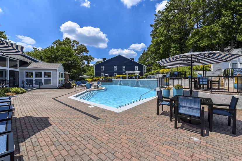 Relaxing pool area at Avana Powers Ferry Apartments with lounge chairs and sun umbrellas, perfect for leisure and recreation