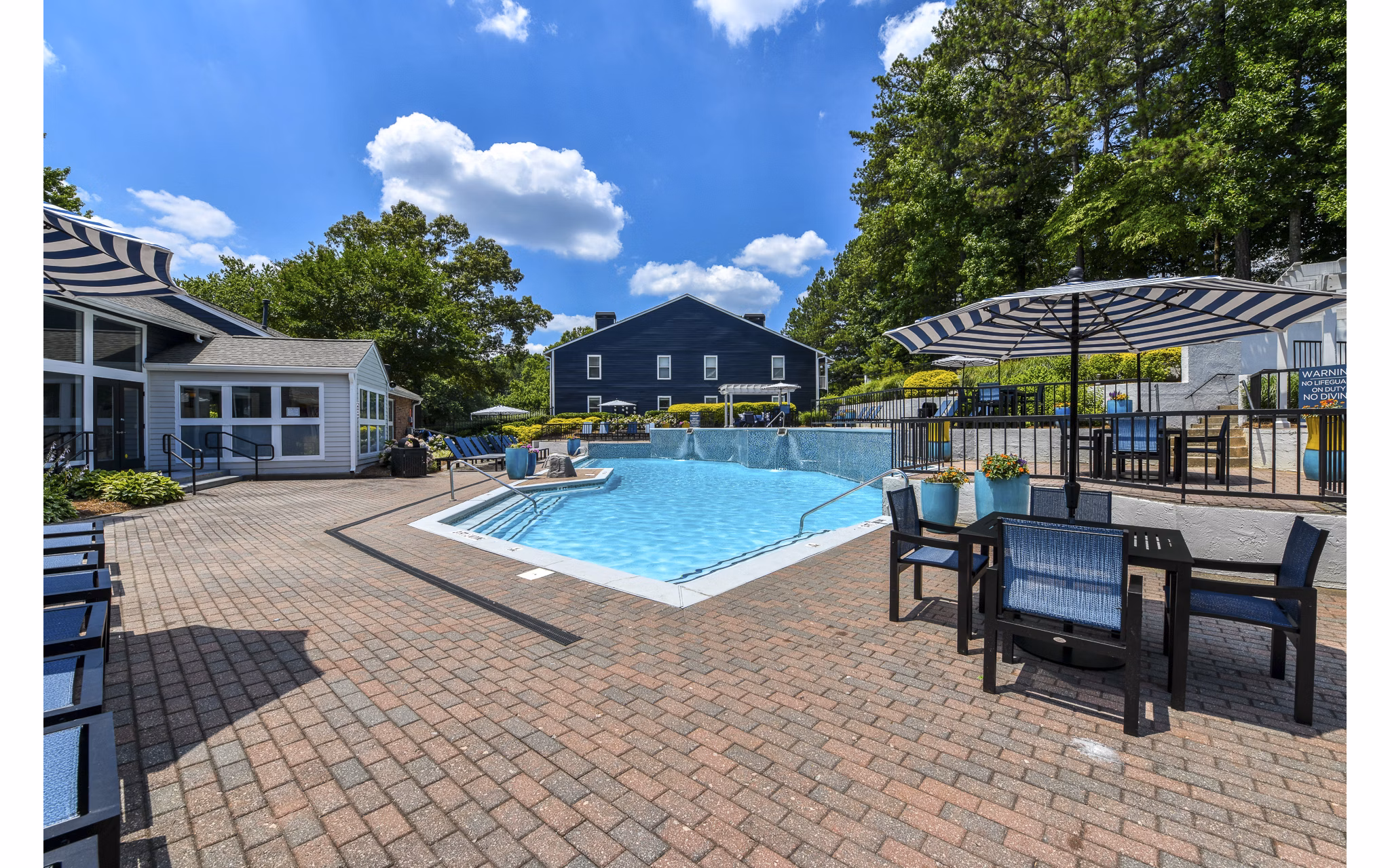 Relaxing pool area at Avana Powers Ferry Apartments with lounge chairs and sun umbrellas, perfect for leisure and recreation