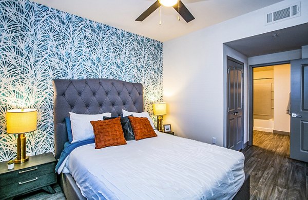 Modern bedroom with king-sized bed and natural lighting at The Alcove Apartments