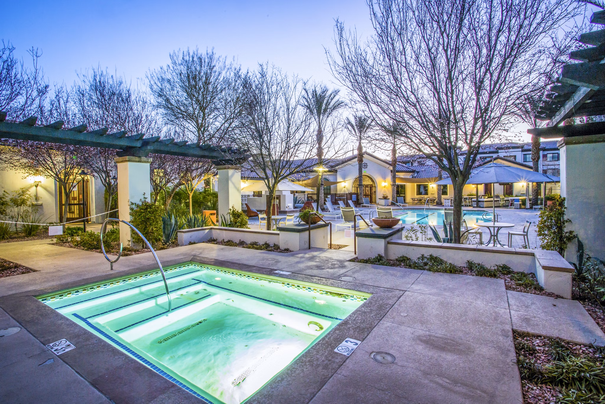 Relaxing hot tub at The Alcove Apartments, surrounded by lush greenery and luxurious seating