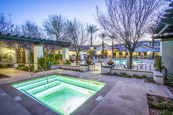 Relaxing hot tub at The Alcove Apartments, surrounded by lush greenery and luxurious seating