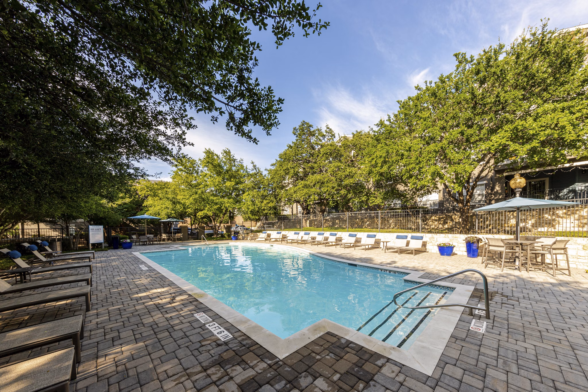 Resort-style outdoor pool at The Highline Apartments with loungers and palm trees, offering a luxurious amenity for residents