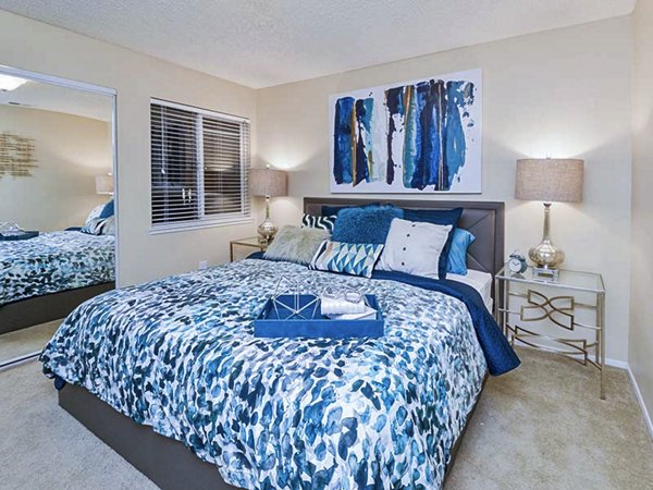 Bedroom with modern furniture and decor at Vineyard Gardens Apartments, featuring cozy bedding and ample natural light for a luxurious living experience