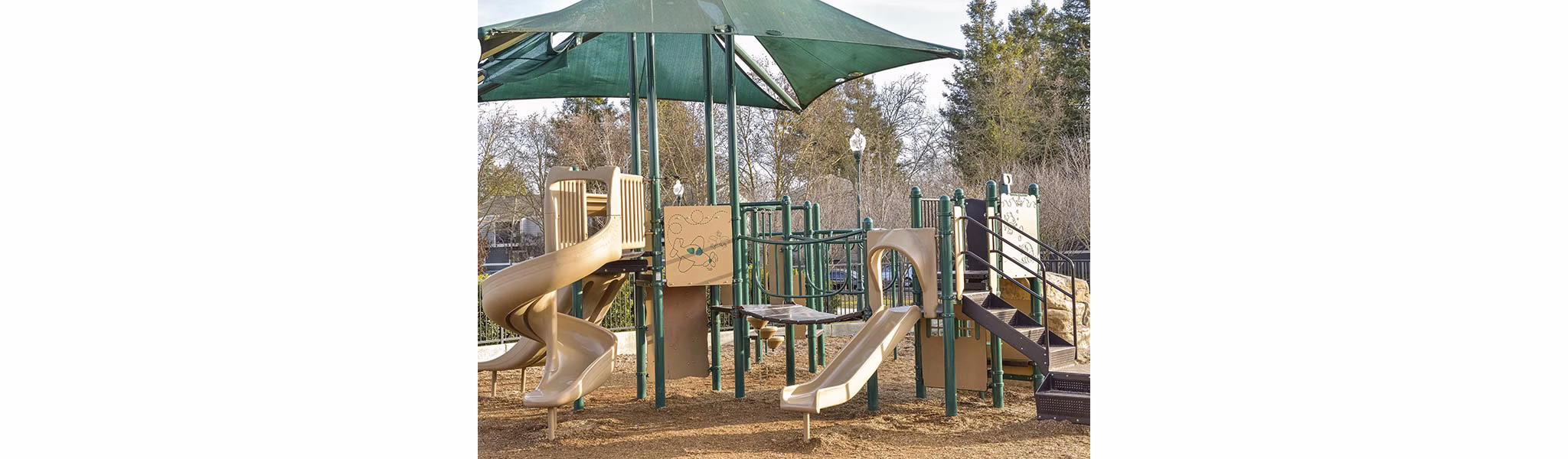 Modern playground surrounded by lush greenery at Vineyard Gardens Apartments, offering family-friendly luxury living spaces