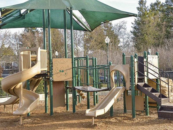 Modern playground surrounded by lush greenery at Vineyard Gardens Apartments, offering family-friendly luxury living spaces