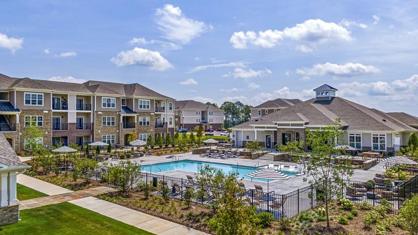 Luxurious outdoor pool at River Oaks Landing Apartments with lounge chairs and greenery, offering relaxation and leisure in a serene environment