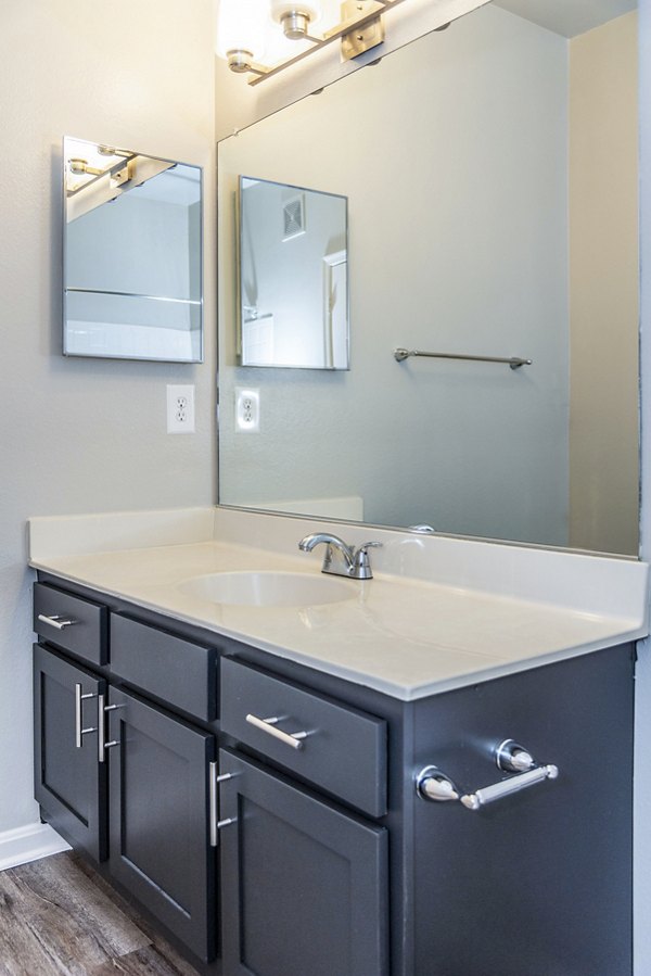 Modern bathroom with large mirrors and sleek fixtures at Pinnacle at Town Center Apartments