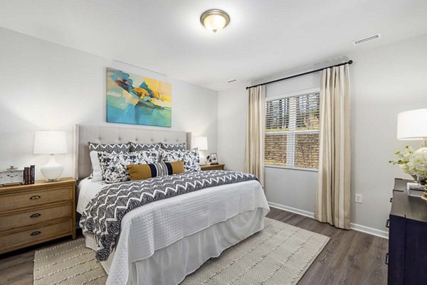 Master bedroom with plush bedding and warm lighting at Ashford Townes Apartments, Greystar's luxury offering in a serene neighborhood