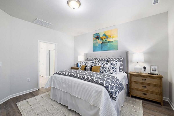 Cozy bedroom with modern decor at Ashford Townes Apartments, featuring plush bedding and ample natural light