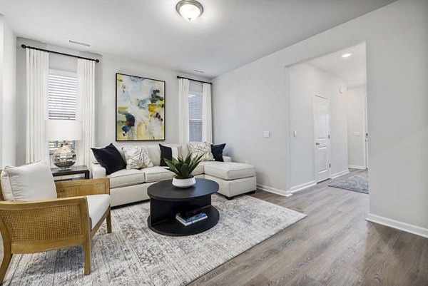 Modern living room featuring stylish decor and large windows at Ashford Townes Apartments