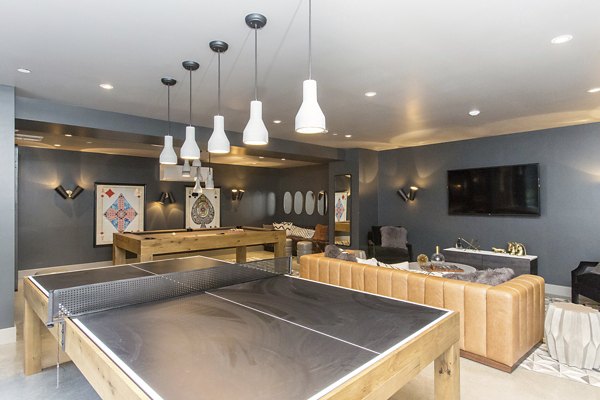 Game room with a ping pong table, pool table, couch, and TV at luxury apartments