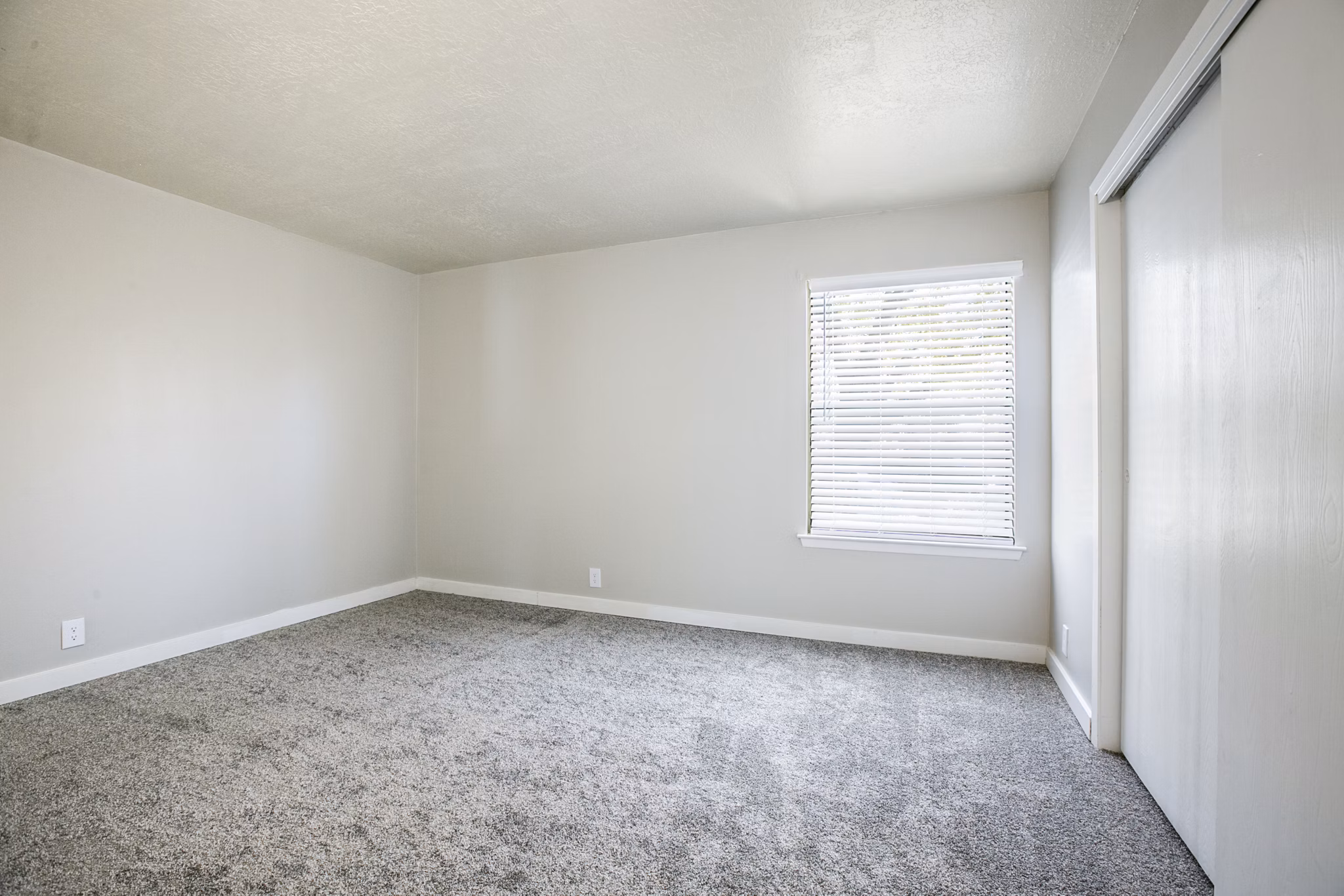 Elegant bedroom with plush bedding and large windows in Canoan Village Apartments