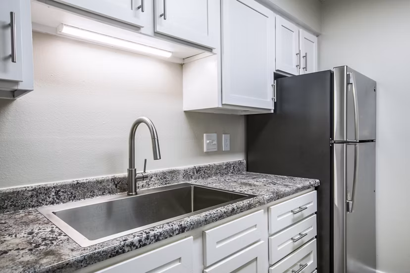 Modern kitchen with stainless steel appliances and granite countertops at Canoan Village Apartments