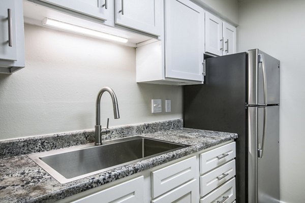 Modern kitchen with stainless steel appliances and granite countertops at Canoan Village Apartments