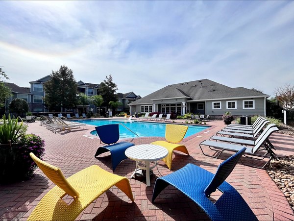 Resort-style outdoor pool at Mirabella Apartments with lounge chairs and umbrellas, offering luxury living by Greystar