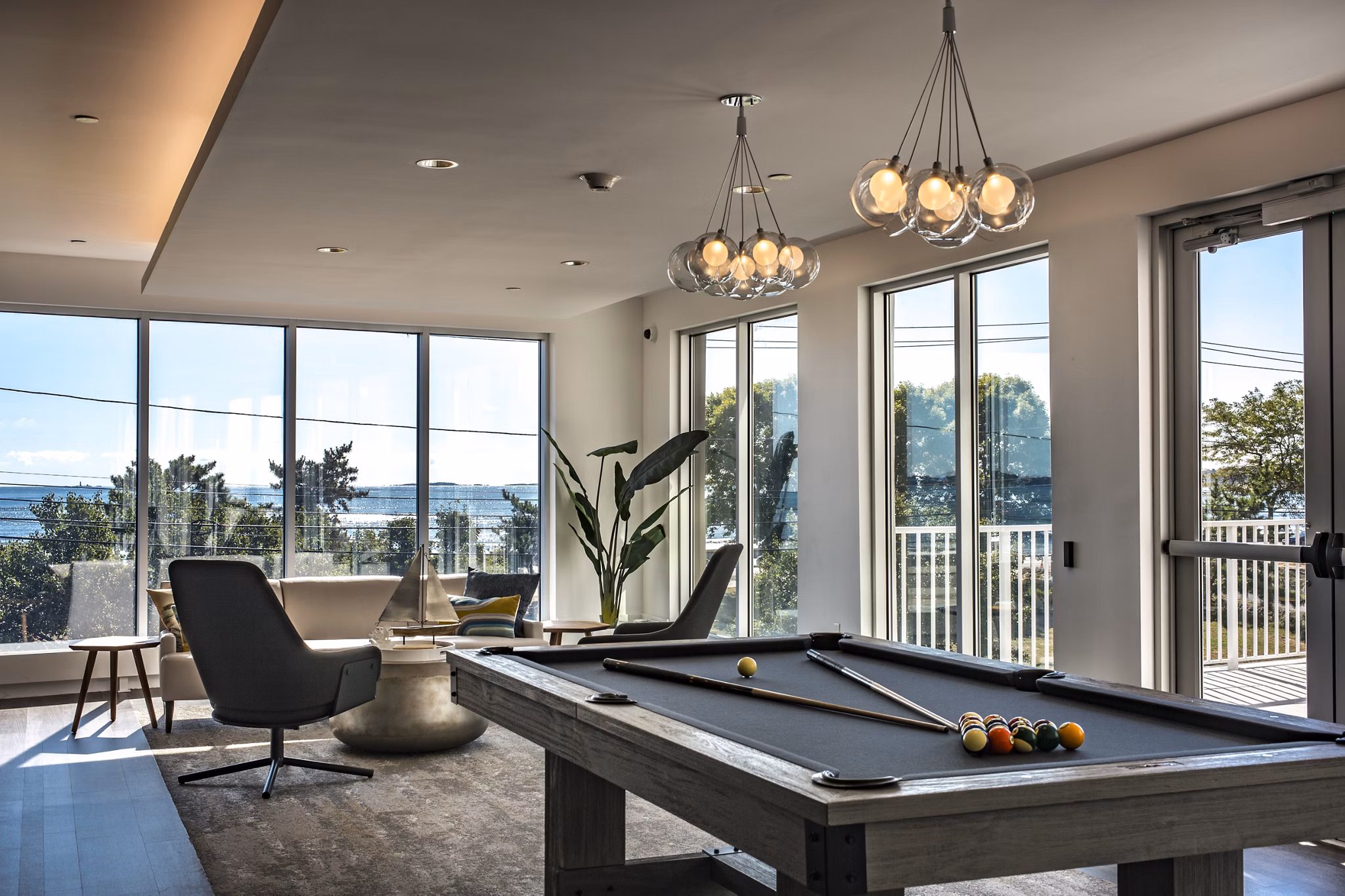 Modern game room with a pool table and large windows in luxury apartments