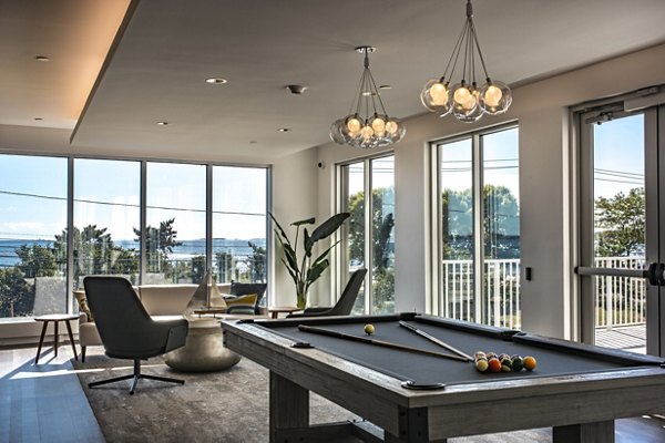 Modern game room with a pool table and large windows in luxury apartments