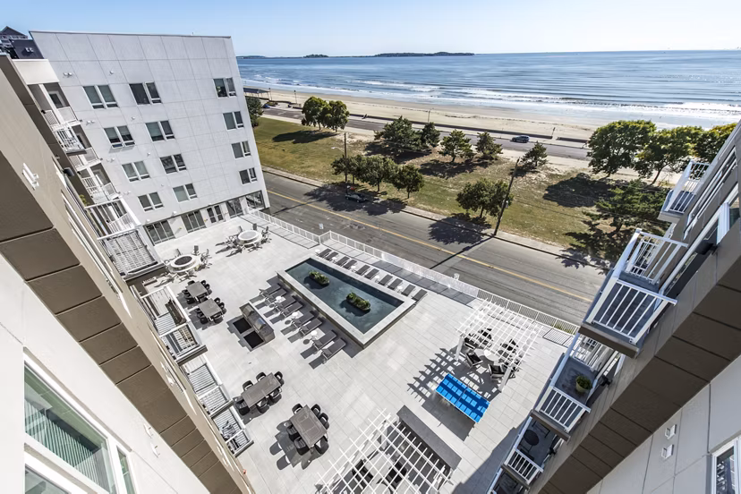 Outdoor swimming pool with lounge chairs and modern apartments in the background at luxury apartments