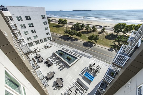 Outdoor swimming pool with lounge chairs and modern apartments in the background at luxury apartments