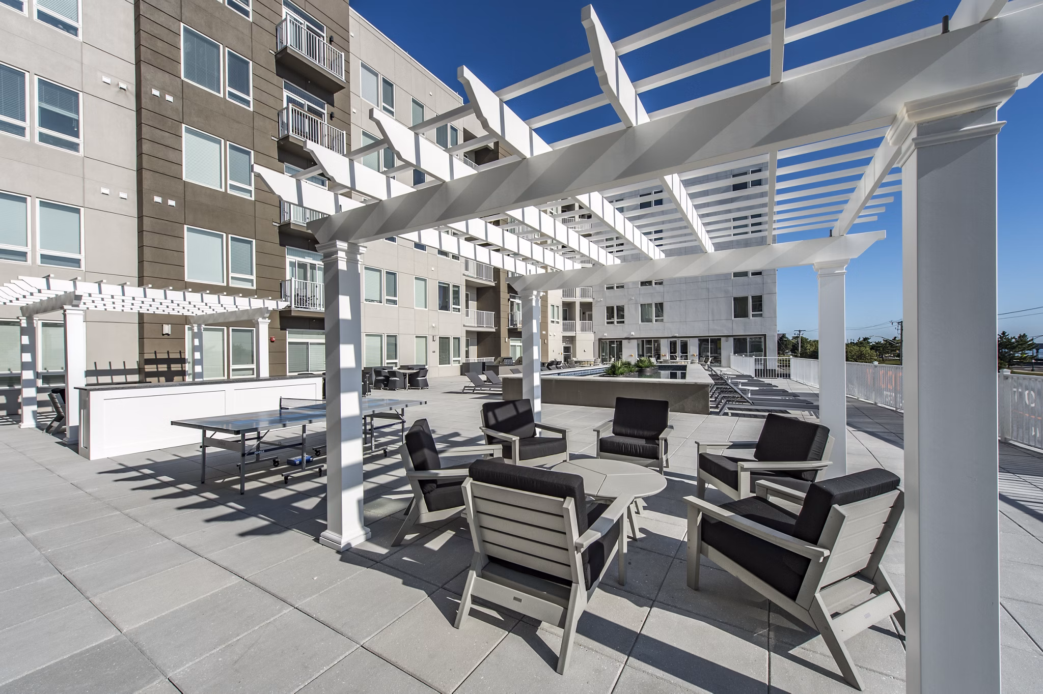 Outdoor patio with comfortable seating, tables, and a stylish pergola at luxury apartments