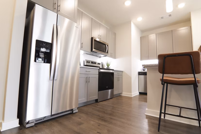 Modern kitchen with stainless steel appliances and granite countertops at The Ravelle at Ridgeview Apartments, luxury living in Greystar community