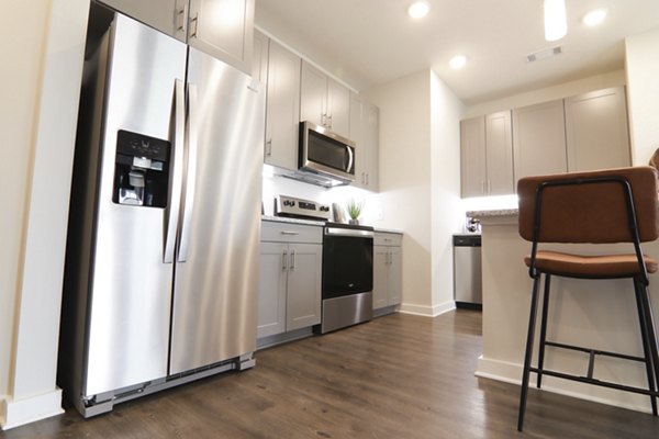 Modern kitchen with stainless steel appliances and granite countertops at The Ravelle at Ridgeview Apartments, luxury living in Greystar community