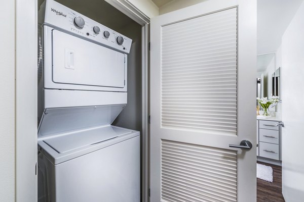 Laundry room with high-efficiency washers and dryers at Alcove Apartments, a luxury community by Greystar