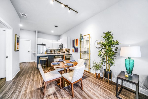 Dining room with elegant chandelier and modern dining set at Beckon Collective Apartments in luxury Greystar community