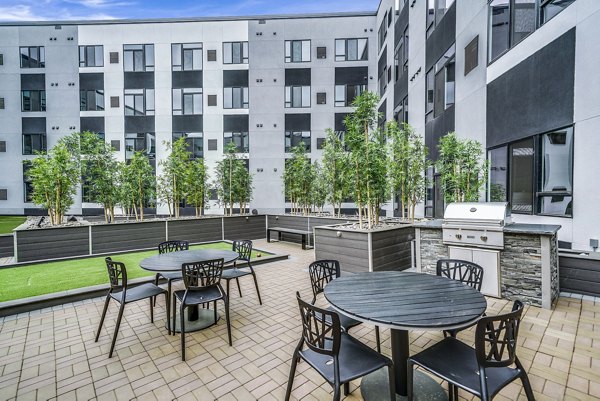 Outdoor grill area with seating at Beckon Collective Apartments for community gatherings and dining