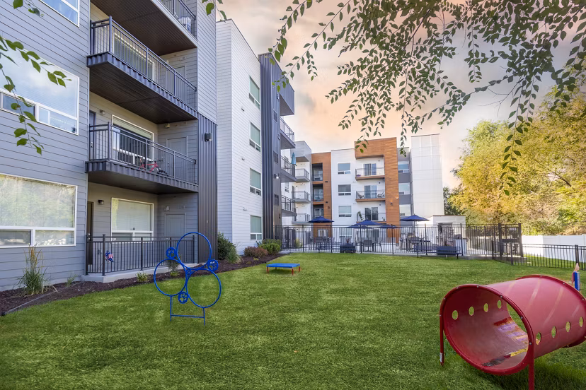Dog park at 644 City Station Apartments: Spacious outdoor play area for pets featuring agility equipment and lush landscaping
