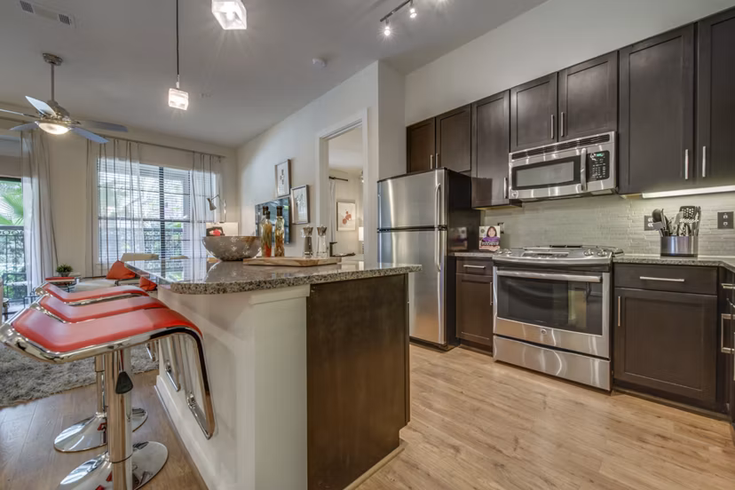 Modern kitchen with stainless steel appliances and marble countertops in Grove at Wilcrest Apartments luxury apartments