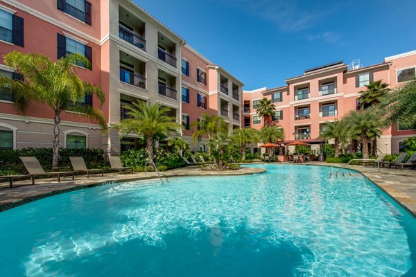 Spacious pool area with lounge chairs at Grove at Wilcrest Apartments, ideal for relaxation and socializing