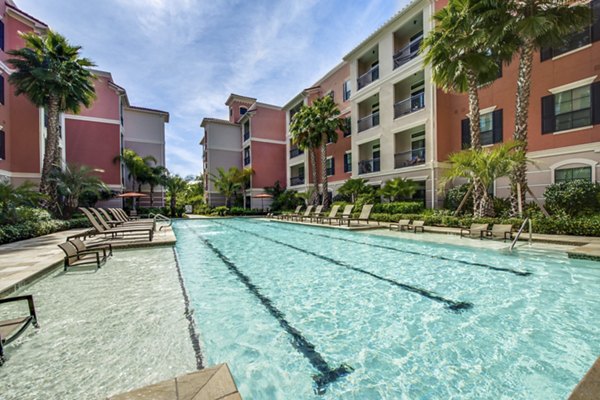 Resort-style pool area with lounge chairs at Grove at Wilcrest Apartments, offering luxury living and relaxation
